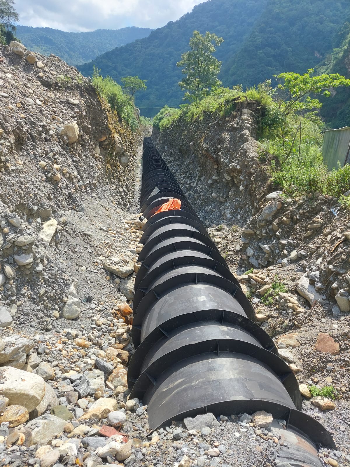 Steel penstock installed along a hillside trench